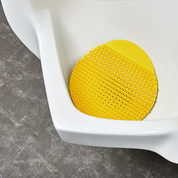 A yellow rubber urinal screen with small holes.