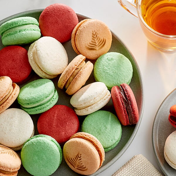 A plate of Macaron Centrale vegan classic macarons on a table with a cup of tea.