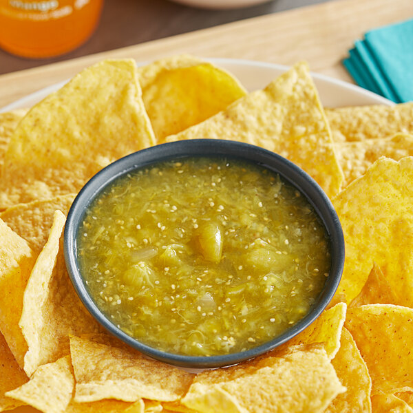 A plate of chips with Del Sol Salsa Verde on a table in a Mexican restaurant.