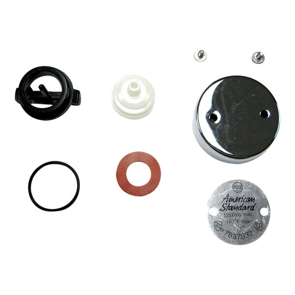 A group of metal American Standard vacuum breaker parts with a round white center.