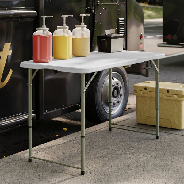 A Lancaster Table & Seating bi-folding table with drinks and condiments on it.