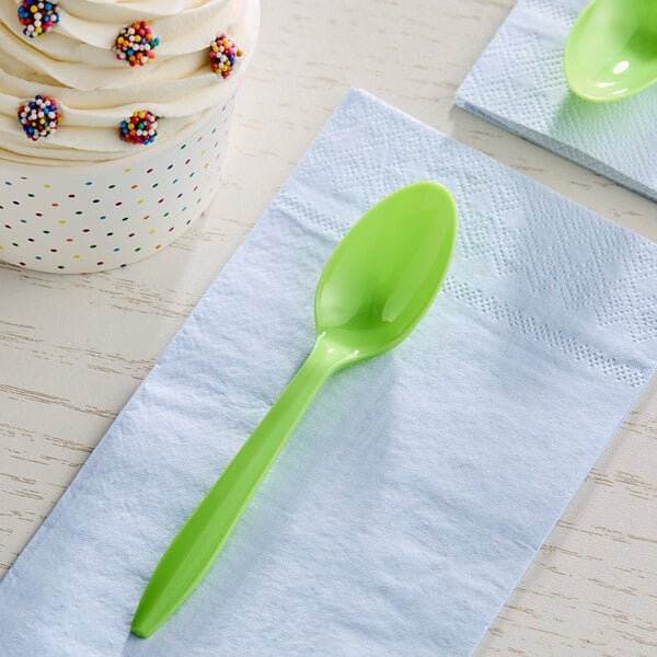 A lime green Choice medium weight plastic teaspoon on a white napkin.