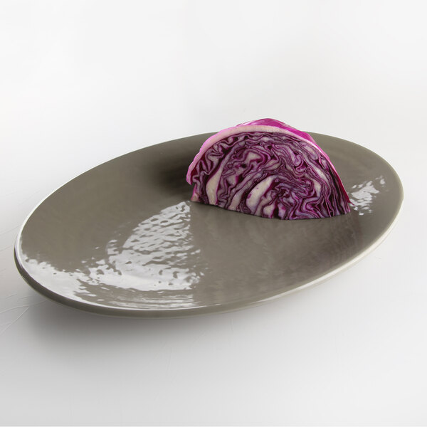 An Elite Global Solutions oval platter with a piece of red cabbage on it.