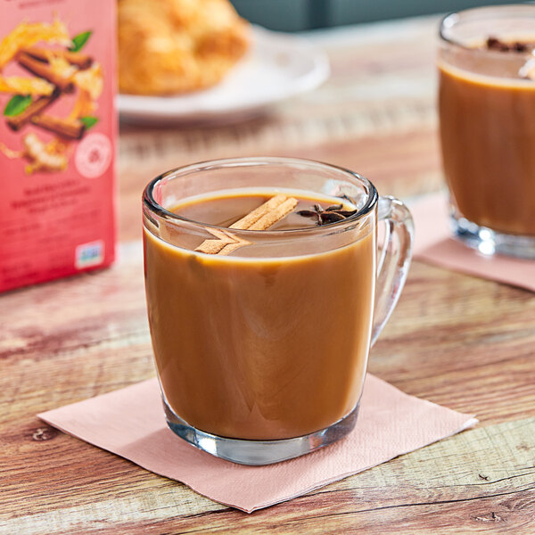 A glass mug of brown Stash Double Spice Chai Latte with cinnamon sticks and star anise.