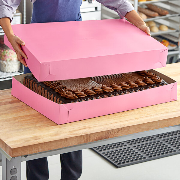 A woman opening a pink Southern Champion Bakery Box.