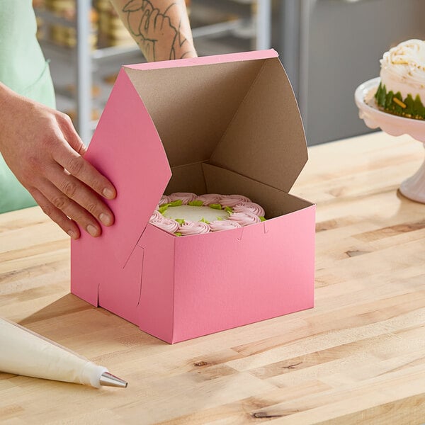 A hand opening a pink Southern Champion cake box.