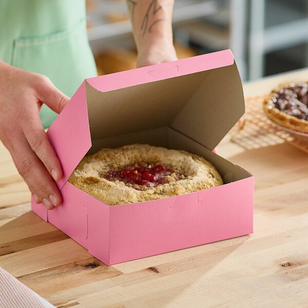 A person putting a pie into a pink Southern Champion pie box.