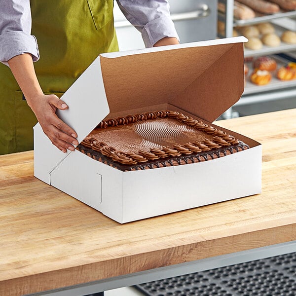 A woman opening a white Southern Champion cake box on a table.