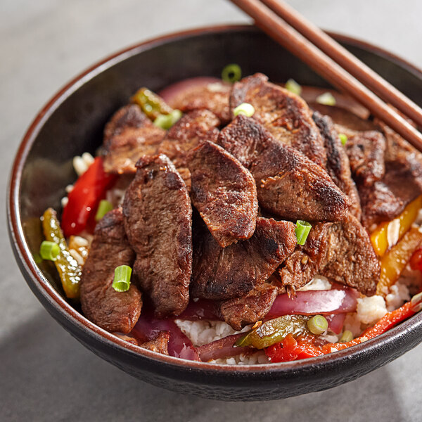 A bowl of Pulmuone Korean BBQ-Style Plant-Based Steak with meat and vegetables on a white background.