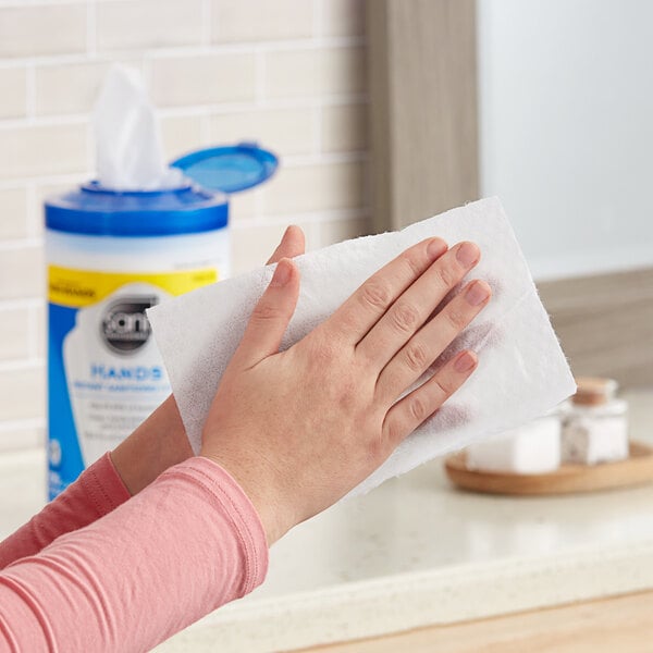 A person cleaning their hands with Sani Professional sanitizing hand wipes.