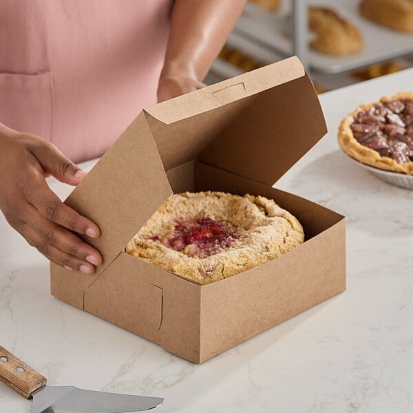 A person cutting a pie into a Southern Champion pie box.