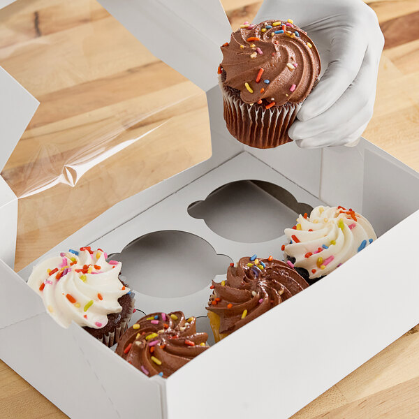 A hand placing a cupcake into a Southern Champion cupcake box.