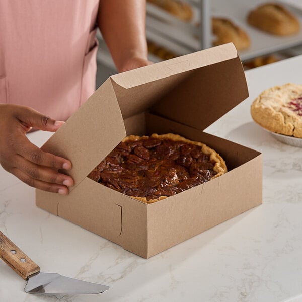 A person opening a Southern Champion kraft pie box to reveal a pie inside.