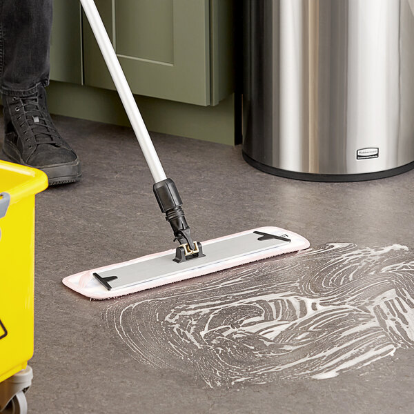 A hand holding a Lavex multi-color microfiber mop pad over a yellow bucket.