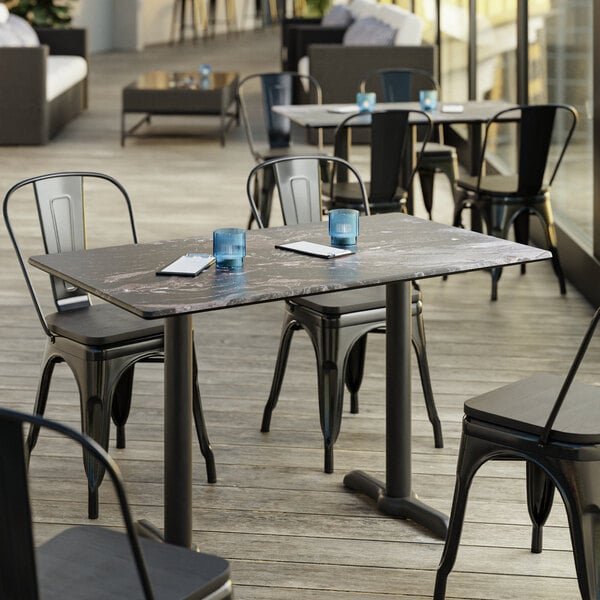 A Lancaster Table & Seating rectangular table with smooth Paladina finish on a patio with chairs.