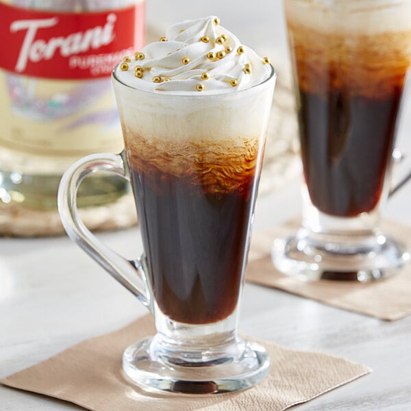 A glass cup of brown liquid flavored with Torani Puremade Diamond syrup on a table.