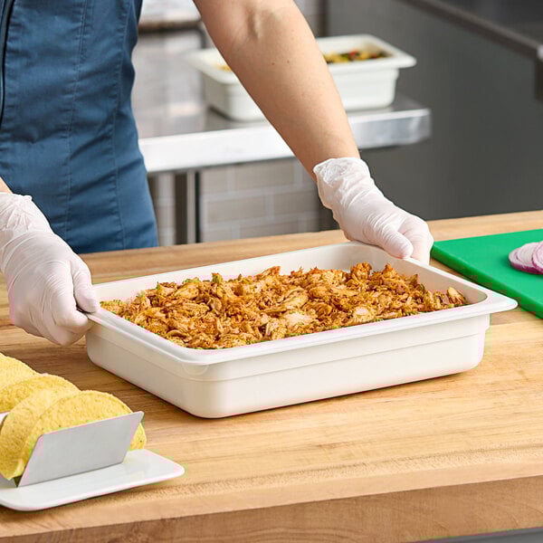 A woman using a white Cambro food pan to hold food.