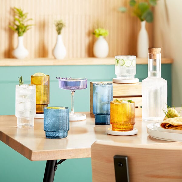 A table with several green Acopa Lore highball glasses and bottles of alcohol.