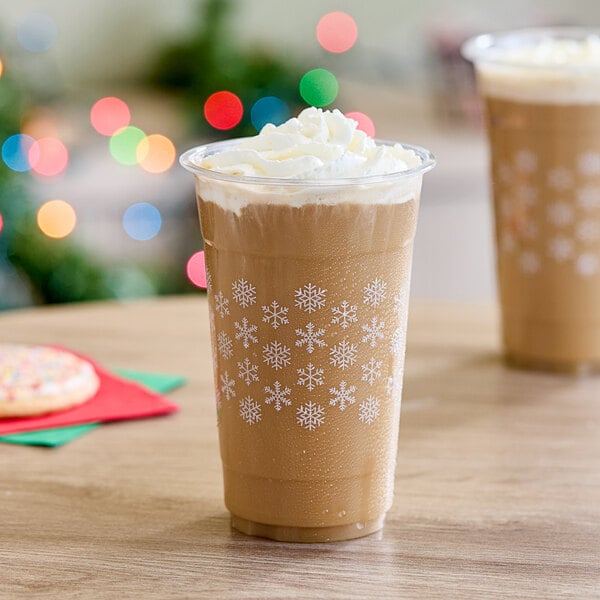 A brown beverage in a Choice snowflake plastic cup with white snowflakes on top.