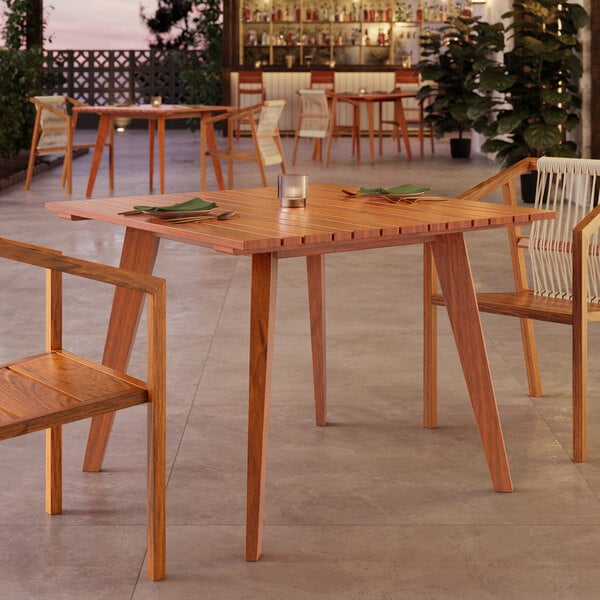 A Lancaster Table & Seating tigerwood table with chairs on an outdoor patio.