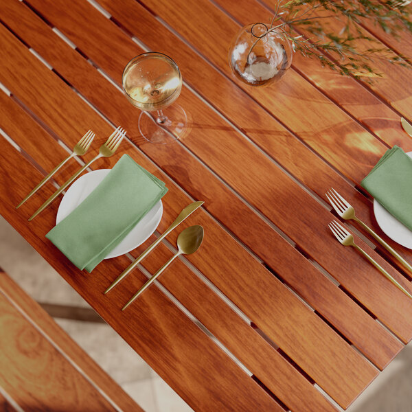 A Lancaster Table & Seating Tigerwood table with plates and silverware on an outdoor patio.