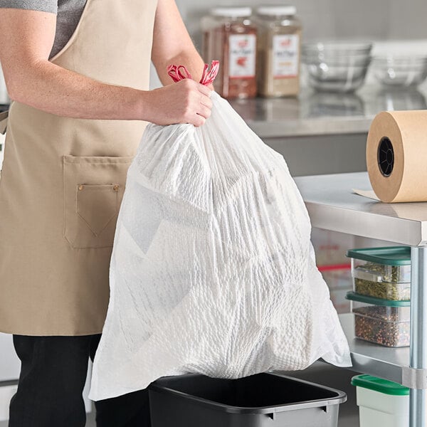 A man in an apron holding a white Lavex plastic bag of trash.