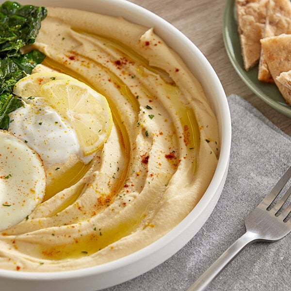 A bowl of hummus with vegetables and spices.