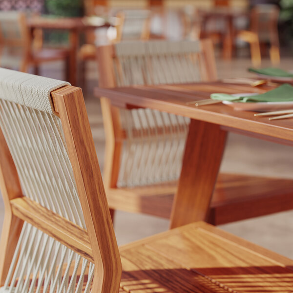 A Lancaster Table & Seating Tigerwood table with chairs on a restaurant patio.