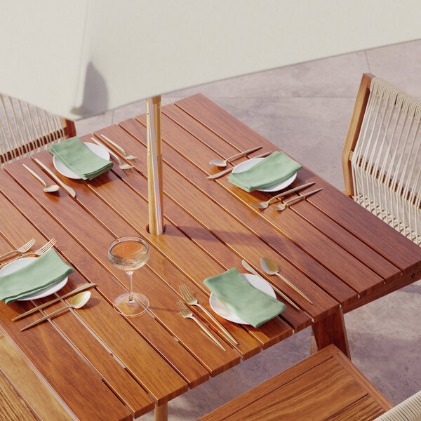 A Lancaster Table & Seating Tigerwood outdoor table set with plates and silverware on it.