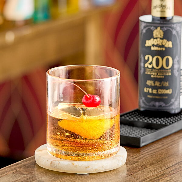 A glass of whiskey with Angostura Aromatic Bitters and a cherry on top.