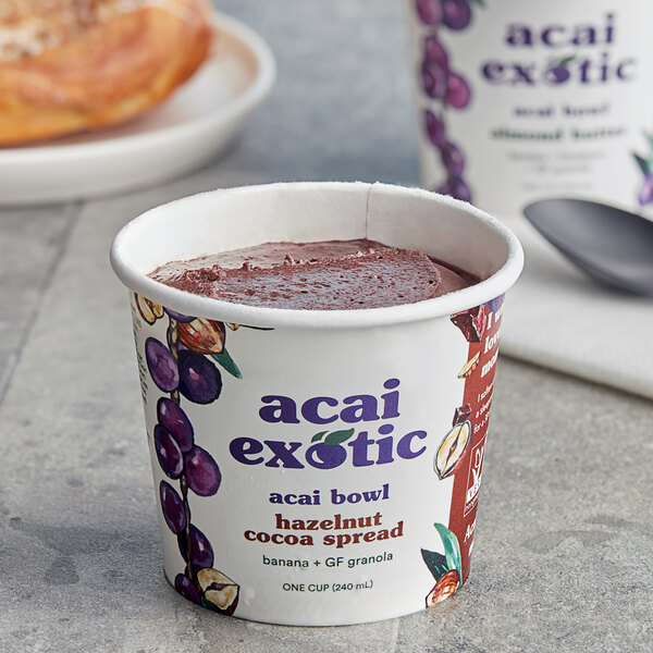A cup of Acai Exotic Hazelnut Cocoa Spread on a table with a spoon.