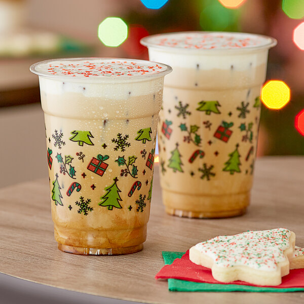 Two Choice holiday cups filled with a drink on a table with a frosted cookie.