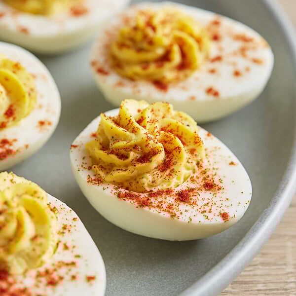 A plate of deviled eggs sprinkled with red paprika.