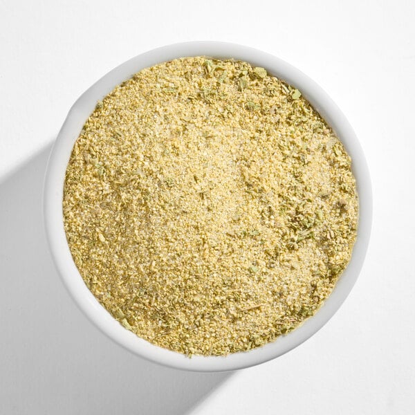 A white bowl filled with a yellowish, finely ground seasoning blend.