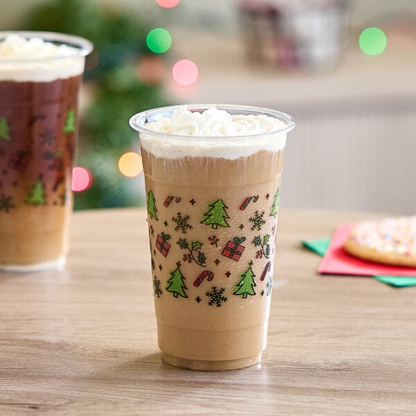 Two Choice Holiday plastic cups filled with whipped cream-topped drinks on a table with Christmas decorations.
