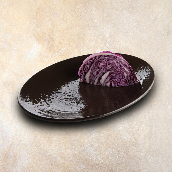 An Elite Global Solutions aubergine-colored oval platter with a piece of red cabbage on it.