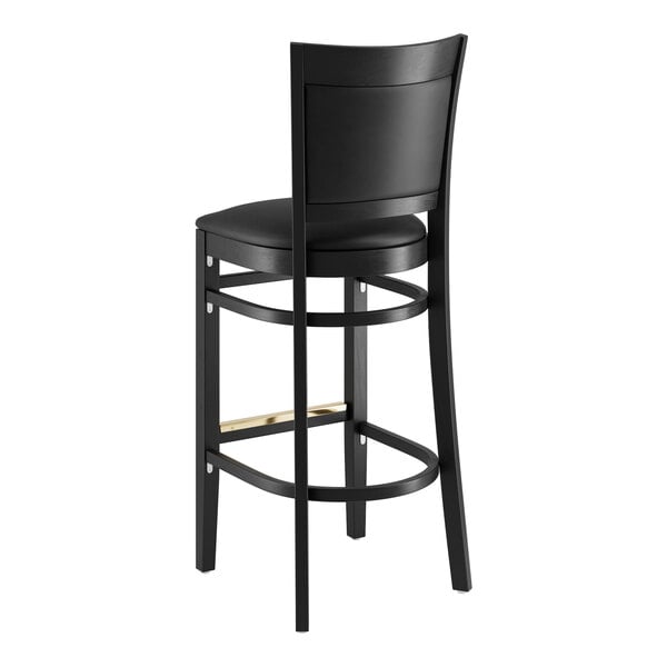 A Lancaster Table & Seating black wood bar stool with black vinyl seat.