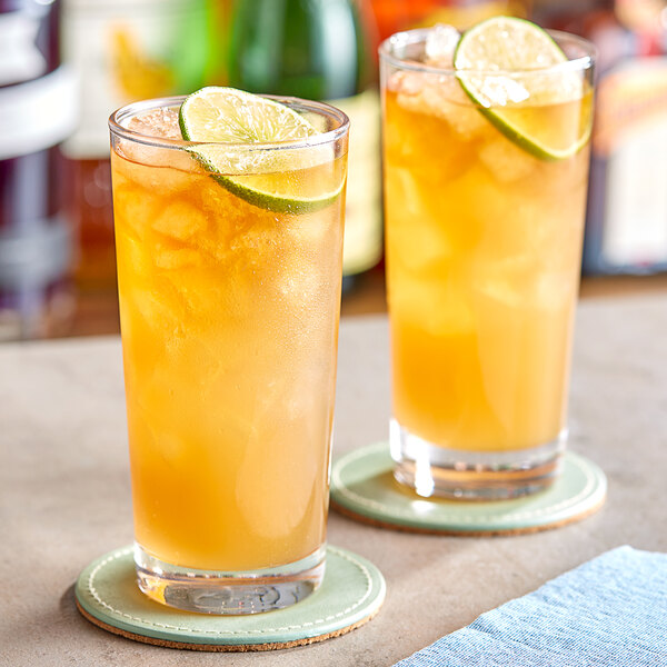 Two glasses of Paradise Ginger Beer with lime slices on a table.