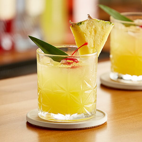 A glass of Paradise Pineapple Juice with a pineapple slice on the rim.