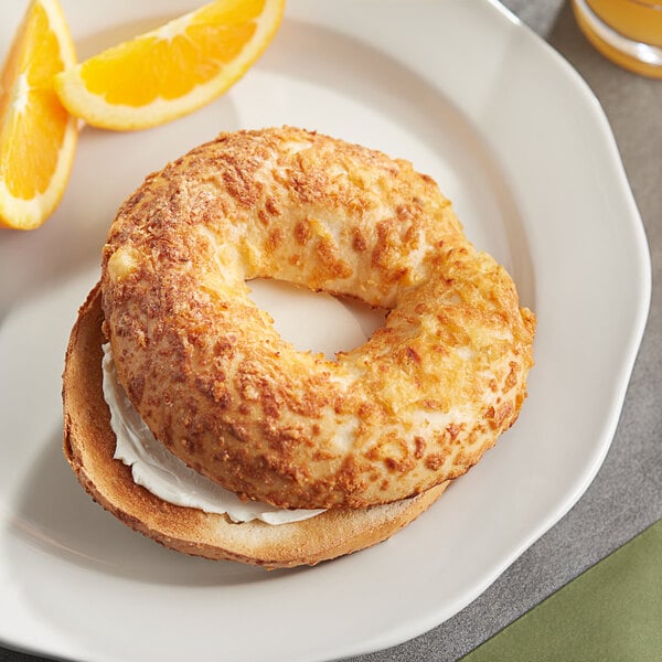 A bagel sandwich with cheddar cheese and orange slices on a plate.