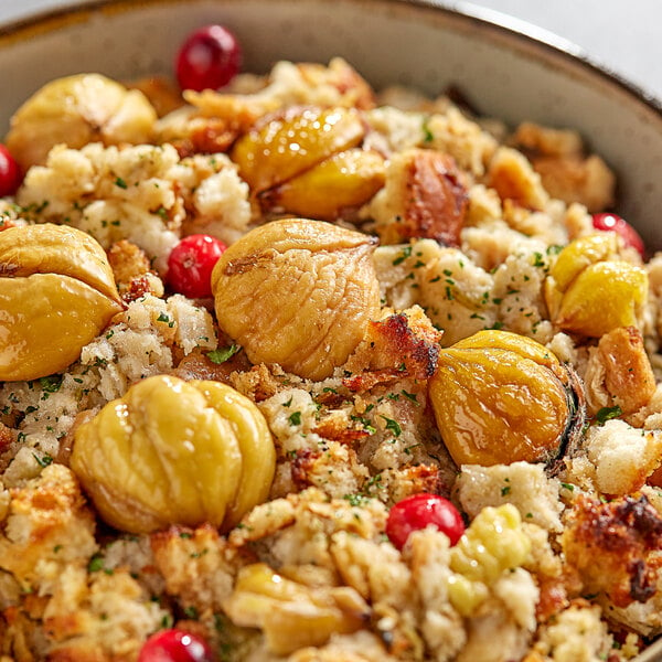 A bowl of stuffing with cranberries and whole raw chestnuts.