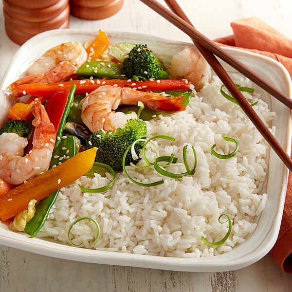 A white plate of Riceland white rice with shrimp, broccoli, and carrots.