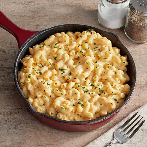 A pan of macaroni and cheese with a fork and spoon on a table.