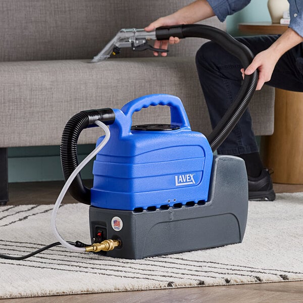 A man using a Lavex carpet extractor to clean a couch.