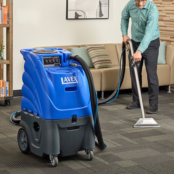 A man using a Lavex heated carpet extractor with hoses on a carpet.