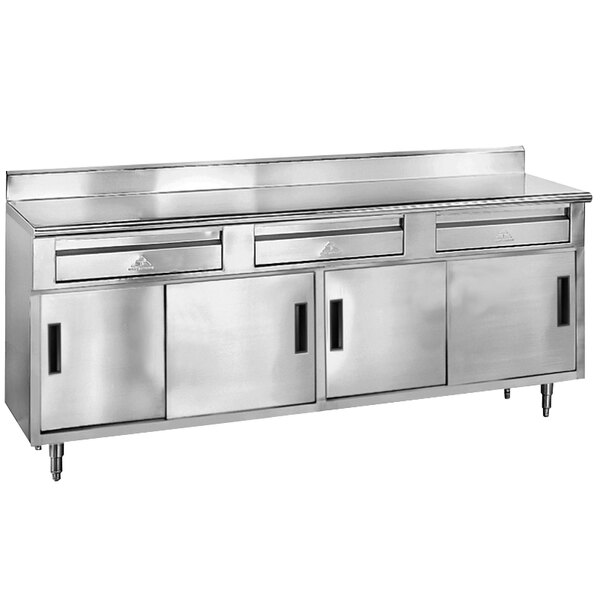 A stainless steel Advance Tabco work table with 3 drawers and 4 sliding doors.