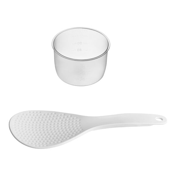 A white plastic rice paddle and a clear plastic measuring cup.