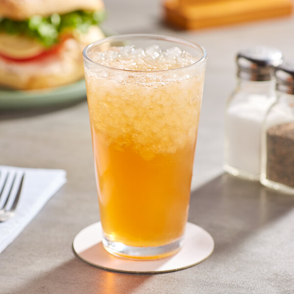 A glass of AriZona Arnold Palmer Lite Half and Half Iced Tea Lemonade on a table with a sandwich.