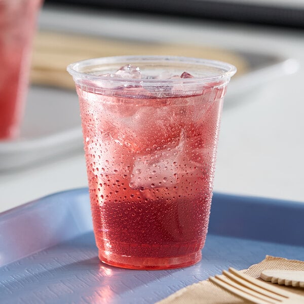 A clear compostable plastic cold cup filled with a red iced beverage.