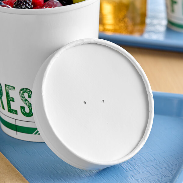 A white Innopak paper cup with a vented lid over a bowl of fruit.